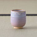 Pale pink-lavender glazed teacup, side view on a tatami mat.