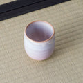 Small pale pink-lavender glazed teacup, side view on a tatami mat.
