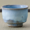 Pale blue crackle-glazed teacup, close side view on a tatami mat.