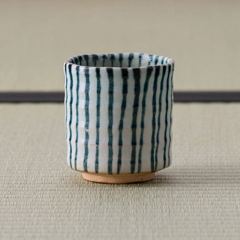 White cup with blue vertical stripes, front view on a tatami mat.