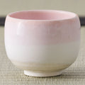 Cup glazed pink at the rim fading to white at the base, close side view.