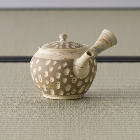 Side view of the white-dotted beige kyusu with the hollow side handle to the right