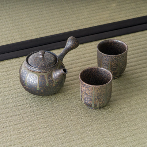 Metallic-grey tokoname tea set — a carved side-handle kyusu with two matching cups, on tatami