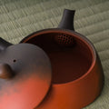 Close-up into the kyusu interior with the lid set ajar, showing the reddish clay inside