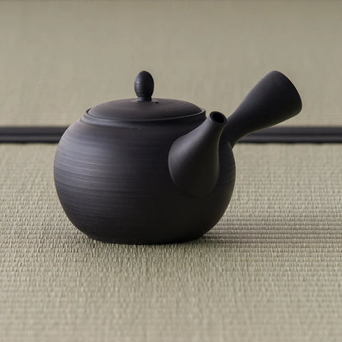 Black kyusu teapot showing the rounded body and side handle from the rear three-quarter