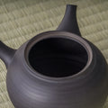 High angle of the black kyusu showing the lid and the curve of the body