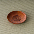 Round reddish-brown turned-wood chataku tea saucer with concentric ring grooves in the center, top view on tatami