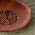 Close-up of the wooden chataku showing the carved concentric ring pattern at its center