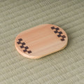 Oval light-wood chataku tea saucer with a dark checkered (ichimatsu) marquetry inlay at one end, top view on tatami