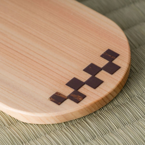 Close-up of the wooden chataku showing the inlaid dark-and-light checkered marquetry pattern