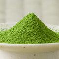 Bright green Uji-no-Mori matcha powder mounded in a ceramic bowl, side view.