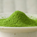 Bright green Uji-Hikari matcha powder mounded in a ceramic bowl, side view.