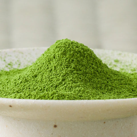 Bright green Uji-Hikari matcha powder mounded in a ceramic bowl, side view.