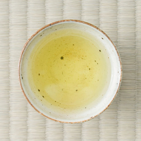 Wakō sencha brewed to a pale greenish-yellow liquor in a speckled white cup, viewed from overhead