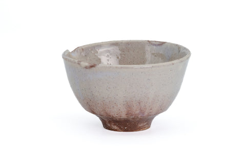 Front view of the beige Hagi-yaki spouted matcha bowl, pouring spout to the side and reddish clay at the base