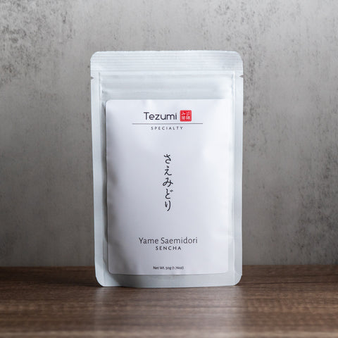 Tezumi Sencha tea package on a wooden surface with a gray background