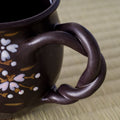Black Weeping Sakura Mug - angled view showing the twisting vine handle and interior