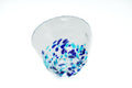 Clear glass teacup with light and dark blue speckles on a white background