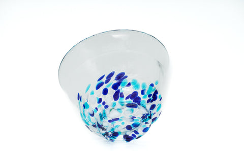 Clear glass teacup with light and dark blue speckles on a white background