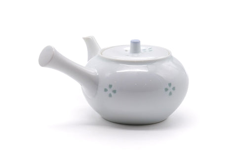 Angled view of the white teapot showing the body, handle and floral motif.