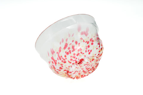 Clear glass matcha bowl with pink and red specks on a white background