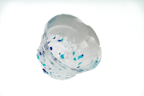 Clear glass teacup with white and blue speckles on a white background