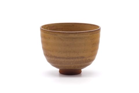 Front view showing the warm mottled yellow-brown glaze of the chawan.