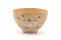 Warm ochre Kyo-yaki matcha bowl painted with colourful paulownia leaf-and-flower motifs, shown from the front.