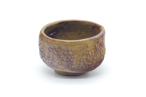 Three-quarter front view of the small brown teacup showing its uneven glazed surface.