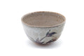 Grey Karatsu chawan with a painted grass-and-floral motif, shown from a three-quarter angle.