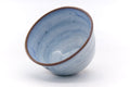 The bowl tipped to reveal its blue glazed interior and darker rim.