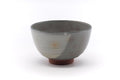 Japanese matcha bowl (chawan), front view, soft grey glaze with faint pink gohon blushes and a reddish clay foot.