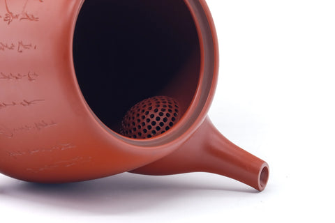 Teapot with the lid removed, showing the interior and ceramic mesh strainer.