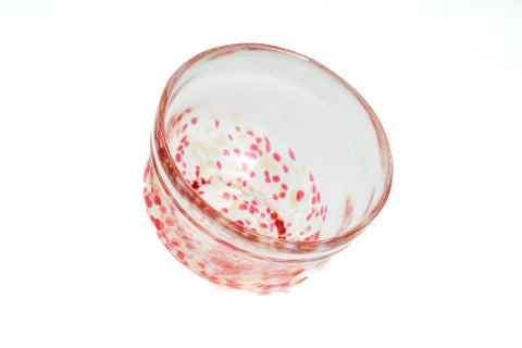 Clear glass matcha bowl with pink and red specks on a white background