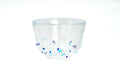 Clear glass matcha bowl with blue specks on a white background