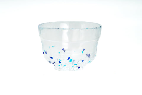 Clear glass matcha bowl with blue specks on a white background
