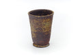Tall tapered teacup with a brown body and mottled yellow ash-glaze speckling, front view.