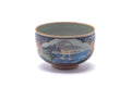 Kutani-yaki yunomi teacup with a blue ground and gold-painted scenic landscape, shown from the front.