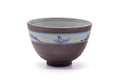 Mountainous-band chawan, front view showing the muted purple body and blue landscape motif near the rim