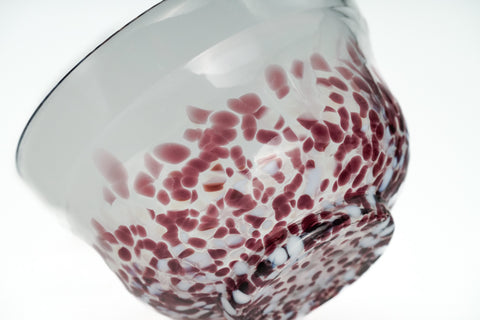 Clear glass matcha bowl with purple specks on a white background