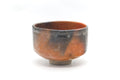 Raku-yaki matcha bowl with a mottled orange, blue and charcoal surface, shown from the side.