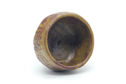The yunomi tilted to reveal its dark glazed interior well.