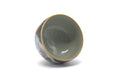 The cup tilted to show the pale glazed interior and gilt rim.