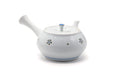 White Arita porcelain kyusu with small painted blossoms and a blue lid knob, front three-quarter view with the spout to the left.