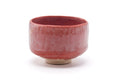 Front view showing the salmon-red raku glaze with mottled dark areas.