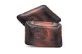 Stack of weathered rectangular copper meimeizara plates, three-quarter view showing the embossed flower.