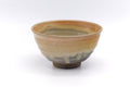Yellow drip-glazed matcha chawan, front view showing the amber glaze softening to a grey-green band near the rim.