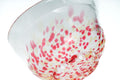 Clear glass matcha bowl with pink and red specks on a white background