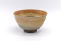 Front view of the yellow drip-glazed chawan with its speckled amber and beige body.