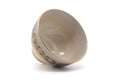 The chawan tilted to show its white glazed interior and gold rim.